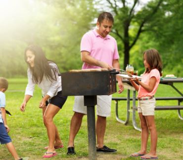 Family grilling together at a park